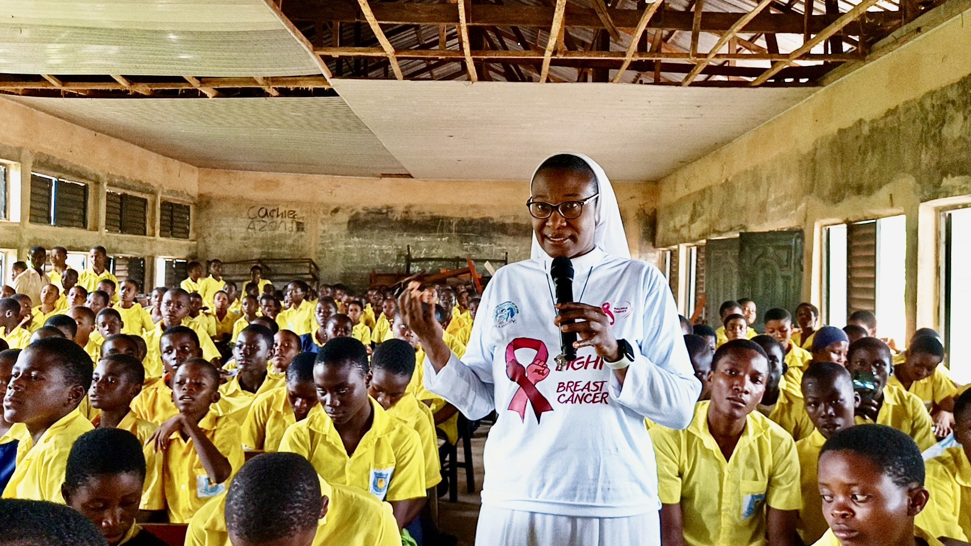 A sister speaks to a hall of young people in yellow PACTPAN shirts